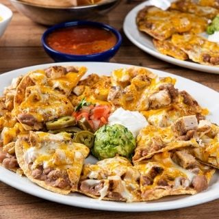 Grande Fajita Nachos: Tostada chips topped with refried beans, fajita chicken or steak and melted mixed cheese, plus sides of guacamole, sour cream, pico de gallo and pickled jalapeños.